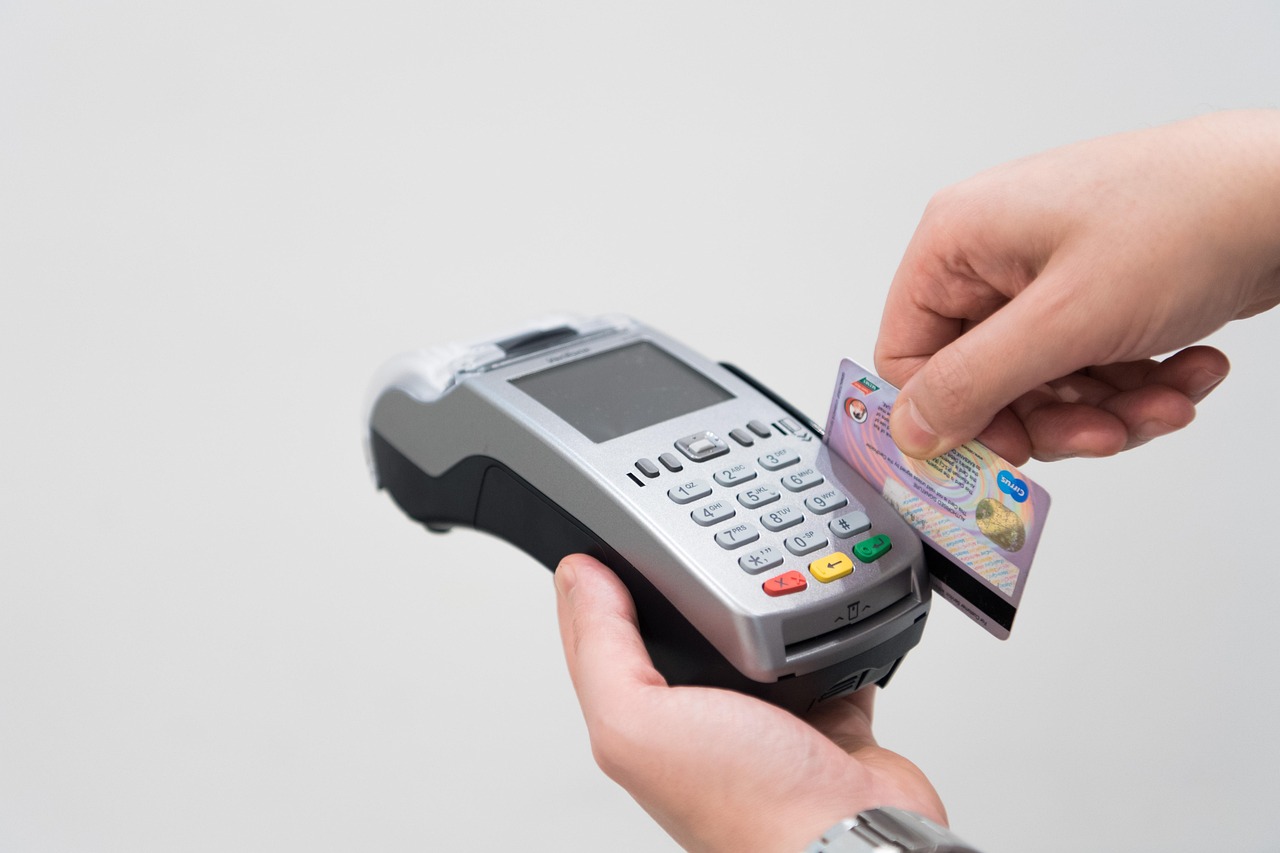 Immagine di un POS con avviso di pagamento rifiutato e carte di credito accanto.